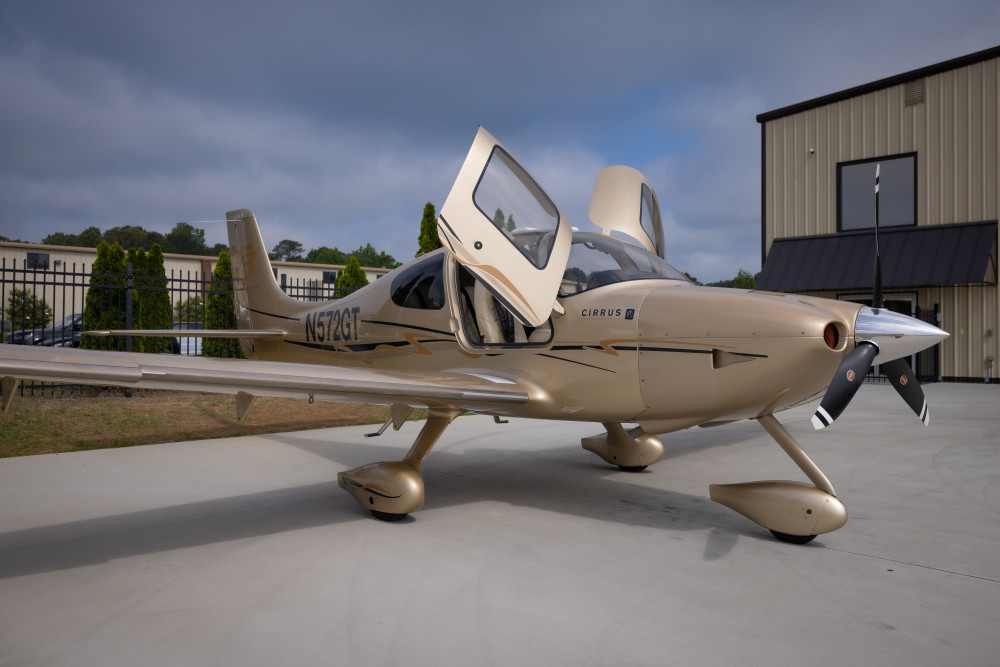 A champagne colored Cirrus SR22 parked with its door open